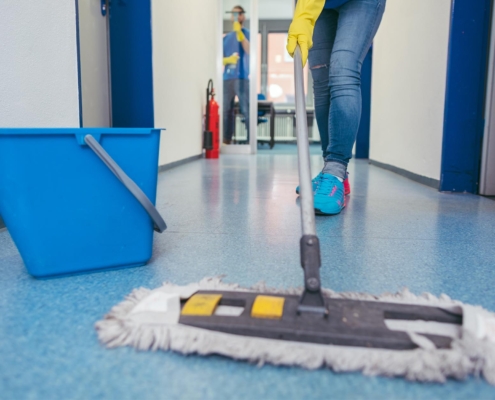 Professional using duster to clean commercial building hallway