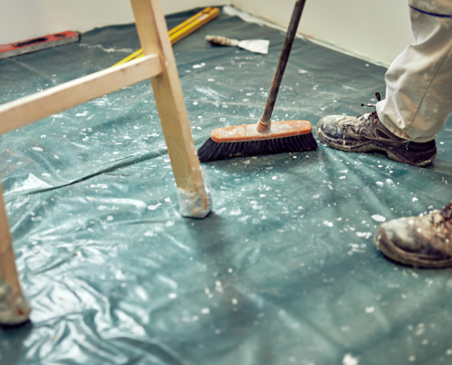 Worker using broom for cleaning dirt during renovaton of the house